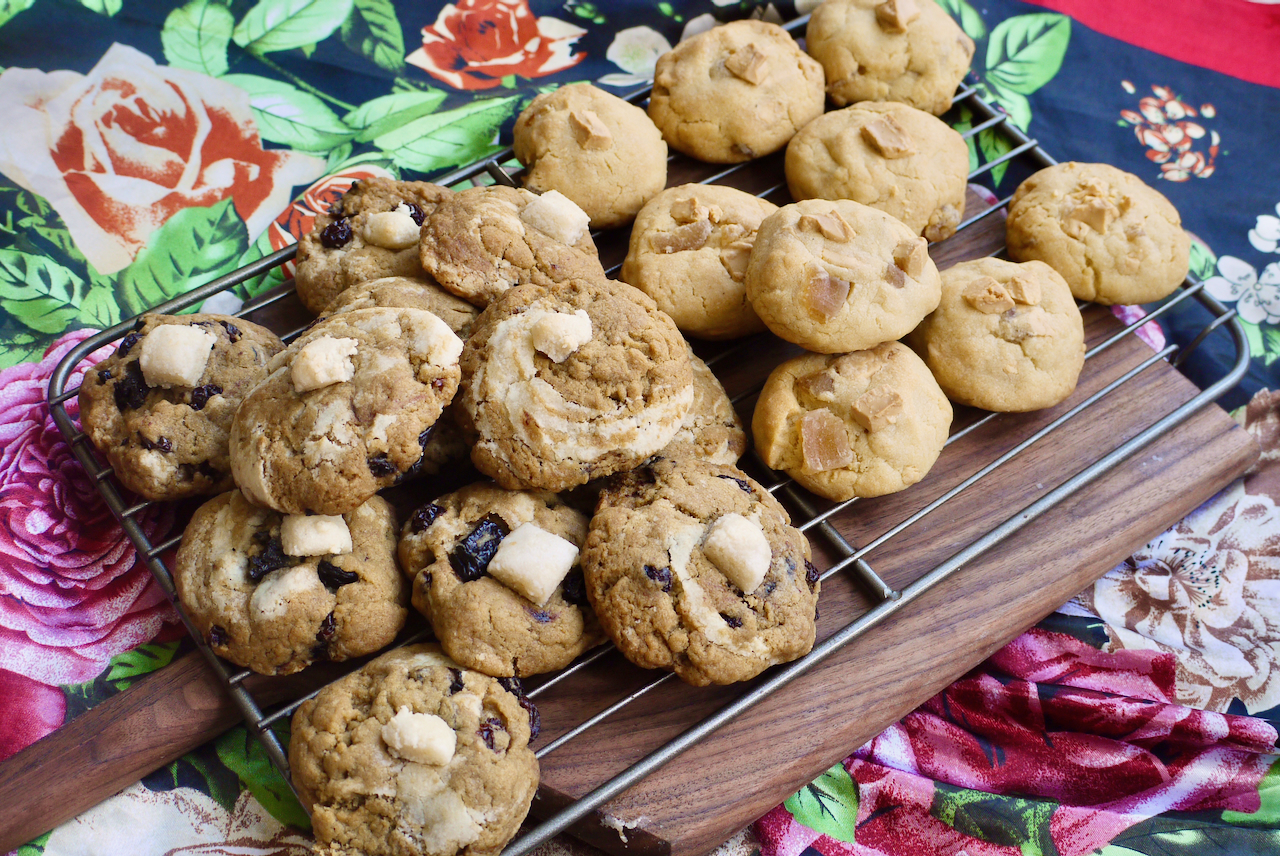 Cookies piled on a rack on top of a wooden board on a floral cloth