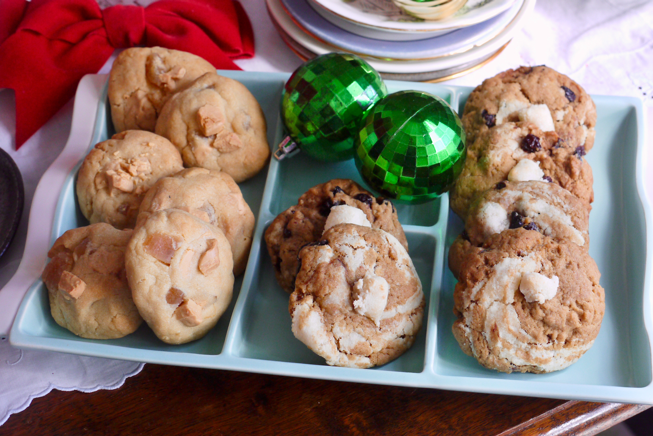 Different cookies on a mint green dish with two bright green Christmas baubles