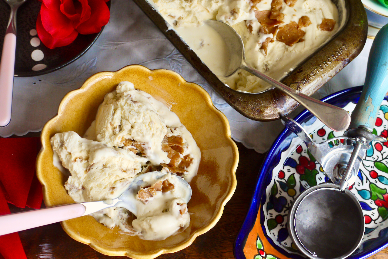 A bowl of ice cream next to an ice cream scoop