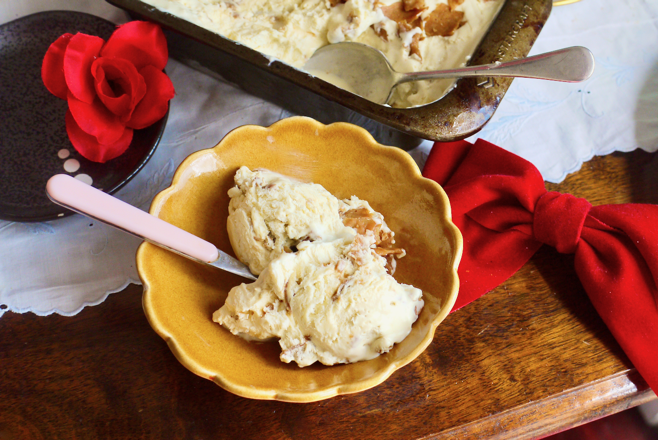 A brown scalloped bowl of ice cream with a pink spoon