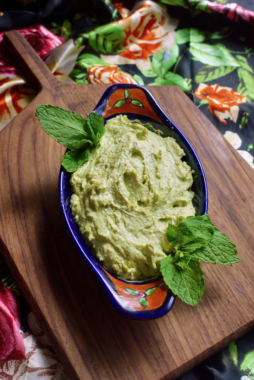 Dip adorned with mint leaves on a wooden board