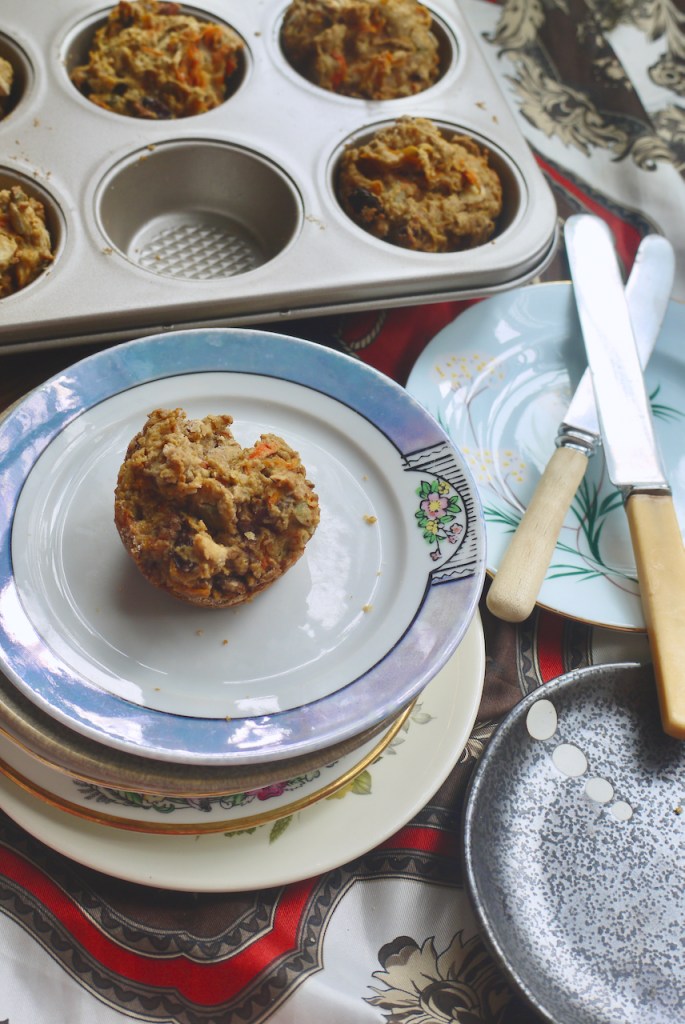 A muffin on a white blue-bordered plate with two butter knives