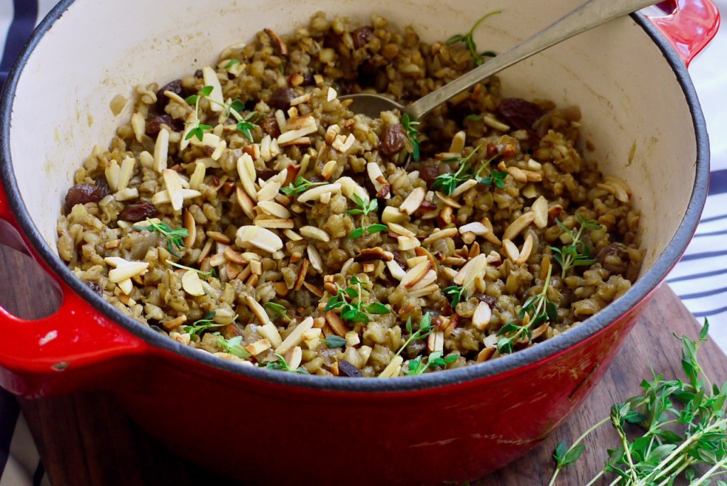 A serving spoon in a red casserole dish of pilaf