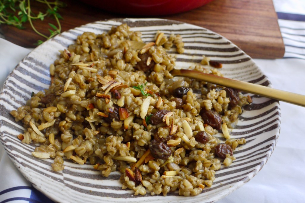 A spoon resting on a black and white striped plate of pilaf