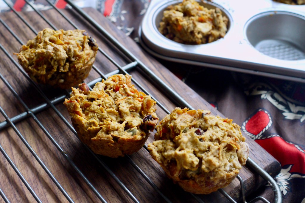 Three carrot granola muffins on a cooling rack