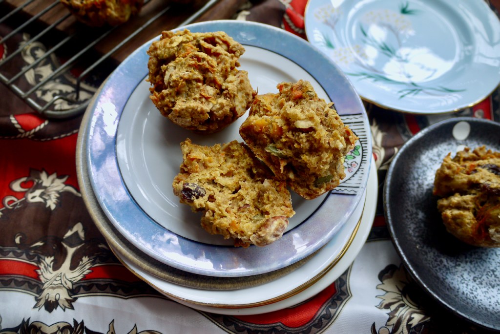 Two muffins, one split, on a white plate with a blue border