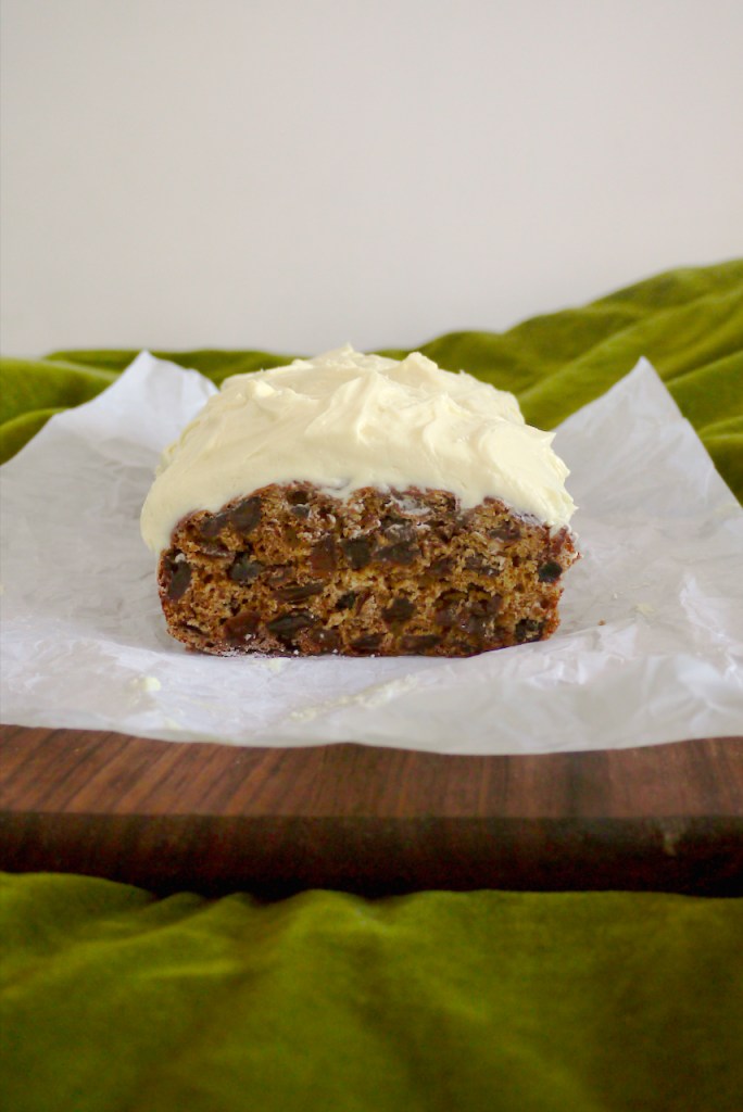 A cut loaf cake on a wooden board on a green cloth