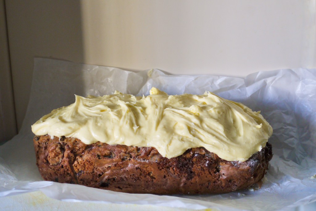 A full iced fruitcake on a piece of crumpled baking paper