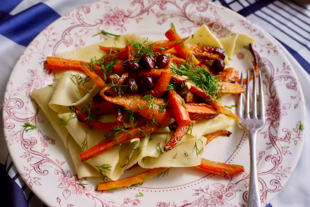 Pappardelle with roasted carrots on a white, pink-bordered plate with a fork