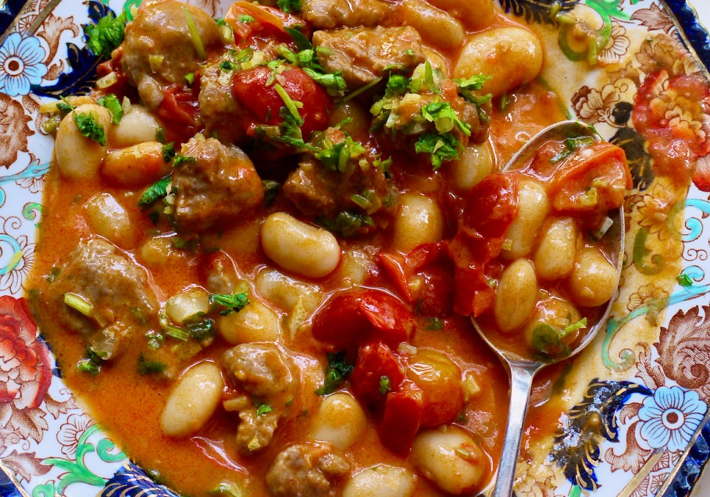 Sausages, beans and gremolata with a spoon.