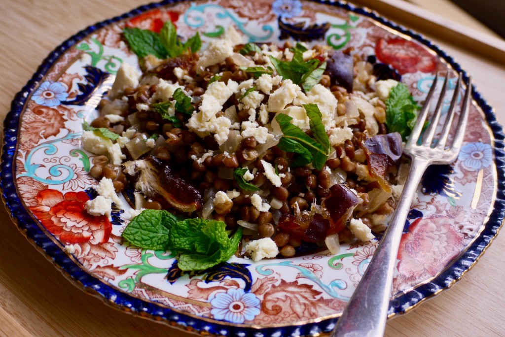A blue and red patterned plate of lentil salad on a wooden table