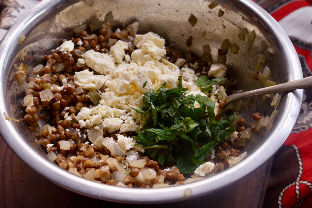 A mixing bowl of lentils, crumbled feta and chopped mint