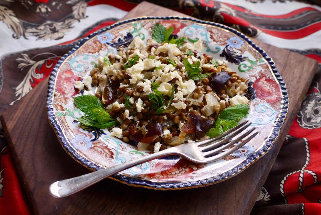 A plate of lentil salad on a wooden board with a fork
