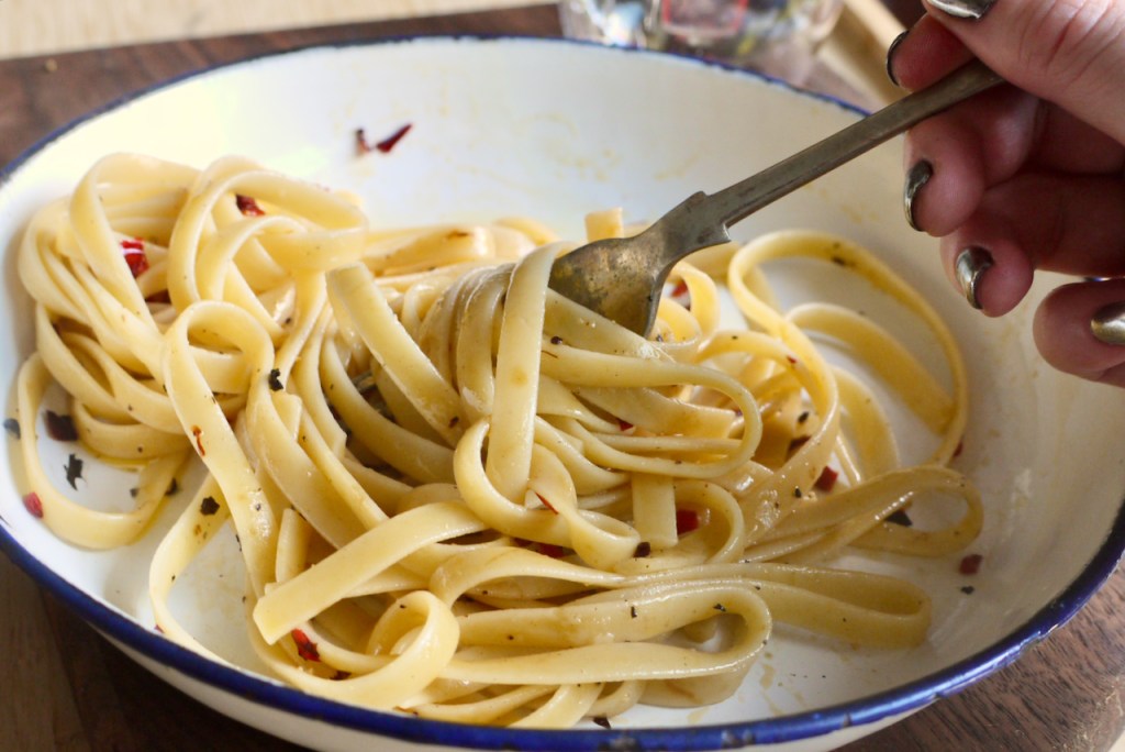 a hand with silver-painted nails twirling a forkful of pasta