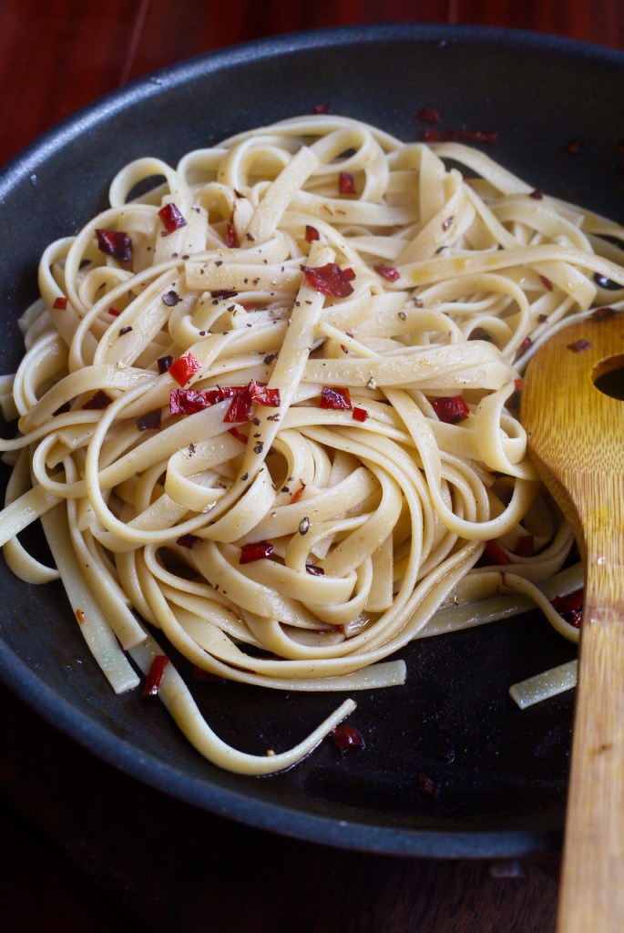 A saucepan of pasta and chilli with a wooden spoon