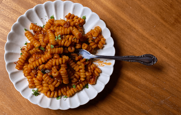 Creamy gochujang tomato pasta on a white fluted plate with a fork. This image links to the recipe.
