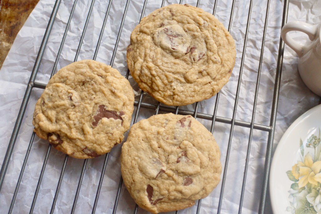 three chocolate chip cookies on a cooling rack