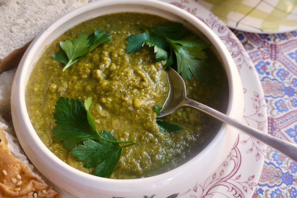 A spoon resting in a bowl of green soup