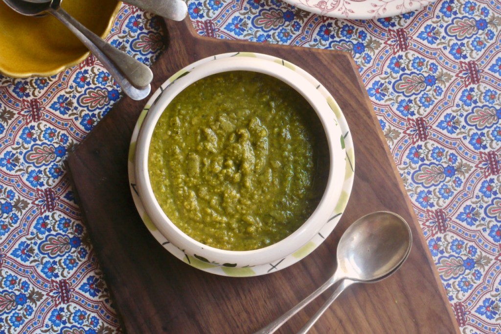 Green soup on a wooden board with two spoons